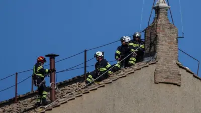 Firefighters work on the roof of the Sistine Chapel to set a chimney ahead of the conclave