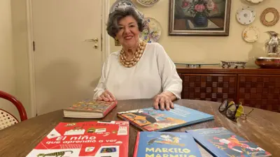 Ruth sorrindo sentada diante7games android apkmesa com vários livros