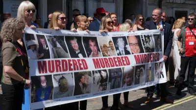 Victims and campaigners stand outside Central Hall in Westminster with banner of dead victims in the infected blood inquiry