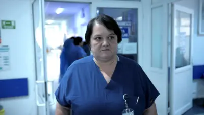 Dr. Oana Goidescu sebész munka közben a buzăui kórházban, kék egyenruhában, középhosszú barna hajjal. 