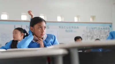 Una niña con uniforme azul en un aula de la escuela. 