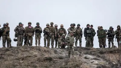 Українські солдати стоять на пагорбі з посохлою травою
