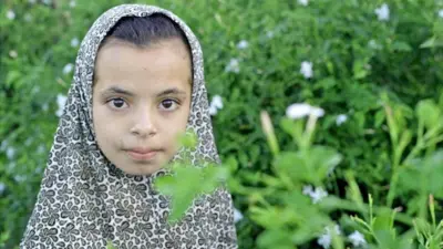 ジャスミン畑に立つ、頭にスカーフを巻いた10歳の少女の写真