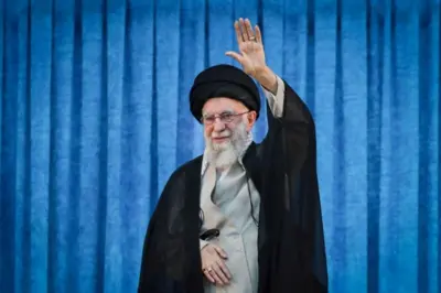 Ali Khamenei usando vestes tradicionais islâmicas e levantando um dos braços em um aceno