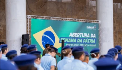 Estudantes de uniforme em escola cívico-militar do Paraná, com placa do programa ao fundo e bandeira do Brasil