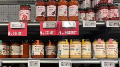 دو قفسه در فروشگاه که شیشه‌های سس پاستا چیده شده‌اند