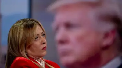 Giorgia Meloni en una entrevista en la televisión pública italiana y detrás una imagen de Donald Trump.