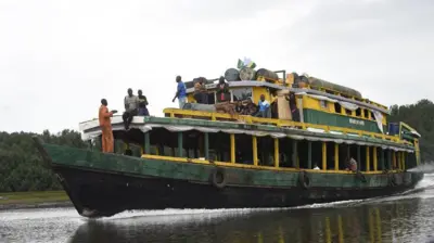A big passenger boat wit some pipo standing on top di deck for Akuku Tori district of Rivers State, Nigeria
