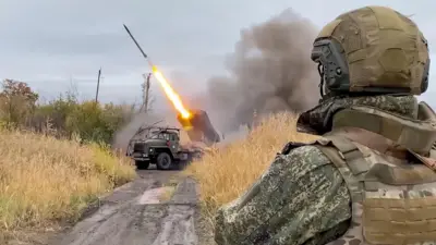 Российский военный (вид со спины) наблюдает за пуском реактивного снаряда из установки «Град»
