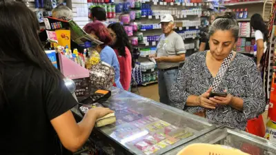 Una mujer paga comida en un supermercado tras la captura de Nicolás Maduro por fuerzas estadounidenses el 6 de enero de 2026 en Caracas, Venezuela. 