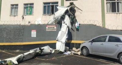 Destroços de avião ao lado de um carro e um muro