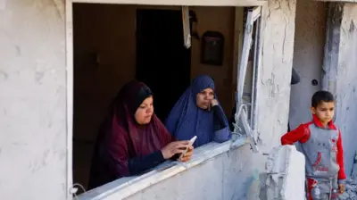 Palestinos olham destruição por janela de casa