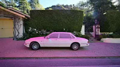 Um carro estacionado coberto por uma camadabets barãopó rosa.