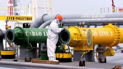 Um homem verifica dois canos, um amarelo e um verde, em uma refinaria chinesa.