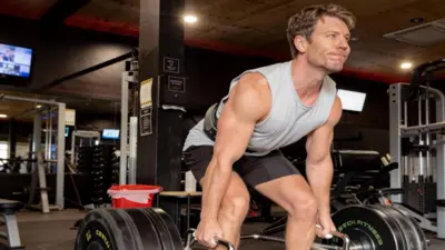 Dr Michael lifting weights at the gym in a grey singlet