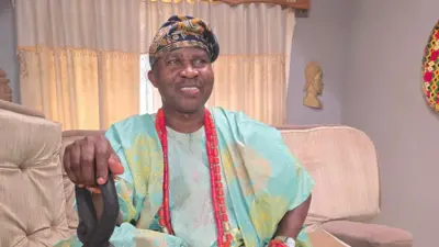 Wale Akorede Okunnu wọ agbada pẹlu fila, o tun mu ọpa lọwọ