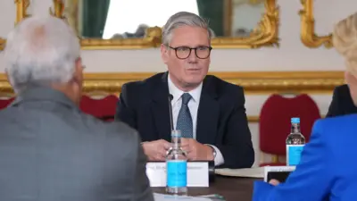 Sir Keir Starmer sitting at a table in Lancaster House, opposite European Commission President Ursula von der Leyen and European Council President Antonio Costa, who have their back to the camera. 