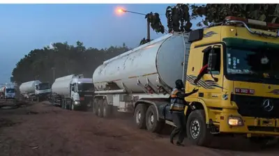 Ọkọ epo mẹrin ati ọkunrin to wa nilẹẹlẹ, nigba ti ọkunrin keji n nawọ silẹ lati inu ọkọ