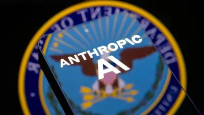 Logo del Departamento de Guerra (o de Defensa) de EE.UU. y un teléfono con el logo de Anthropic en la pantalla