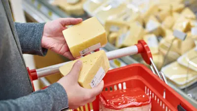 Mãos de consumidor escolhendo queijos num supermercado