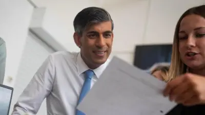 Rishi Sunak being shown a document by a woman