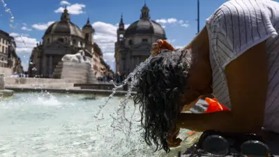 Женщина окунает голову в фонтан на фоне собора