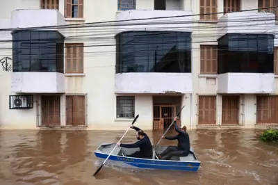 Dois homens em canoa passando em frente a prédio