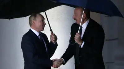 Путин и Алиев стоят под дождем с зонтиками в руках.