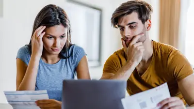 Worried-looking couple looking at a laptop computer