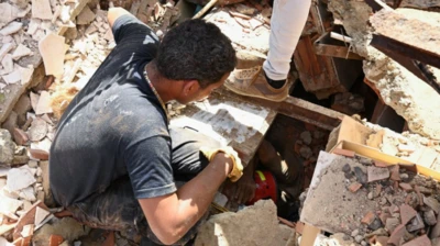 Homem olha por um buraco enquanto socorristas procuram sobreviventes
