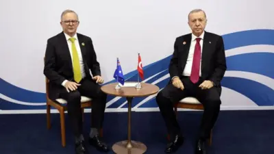 Albanese ve Erdoğan küçük bir masanın iki yanında oturuyor ve kameraya bakıyorlar.