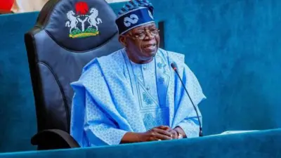Aare Bola Tinubu wọ aṣọ agbada alawọ aro pẹlu fila alawọ kan naa. O n wo ọọkan, o si n rẹrin-in musẹ bo ṣe so ọwọ rẹ mejeeji pọ