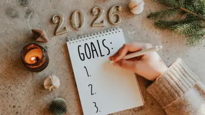 Mão de pessoa não identificada escreve objetivos para 2026 no Ano Novo