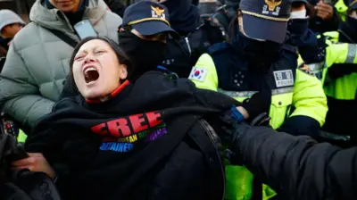 Police officers remove supporters of impeached South Korean President Yoon Suk Yeol from outside his official residence in Seoul, South Korea, on January 2, 2025.