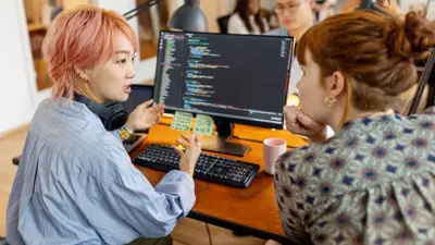 Co-workers discuss in front of a computer screen showing code