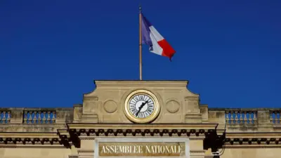 The French National Assembly building in Paris, with the French flag flying above it 