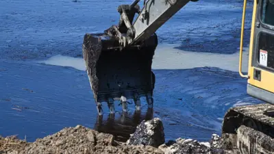 экскаватор чистит воду от нефтяных загрязений