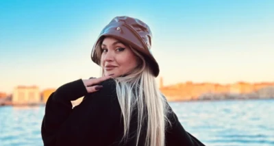 Ülkenin kuzeyindeki Iasi şehrinden bir influencer olan Cristina Horez, kameraya omuz üzerinden bakan bir poz veriyor, eli çenesinde, saçları sarı ve kafasında bir şapka var. Arkada da güneşli bir günde deniz var.