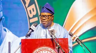 Godswill Akpabio wear sky blue cloth wit Navy blue cap and eyeglasses as e stand for red podium wit three different branded microphones.