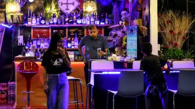 A group of three people at a bar in Laos at night