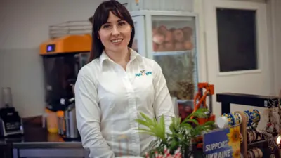 Maryna with brown hair and wearing a white shirt smiles at the camera