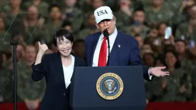 トランプ氏と高市氏が演台に並んで立っている。背後には迷彩服を着た米兵がたくさん並んでいる