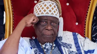 Ogiyan ti ilu Ejigbo, Ọba Omowonuola Oyeyode fi ọwọ si ẹgbẹ ori, o n wo ọọkan