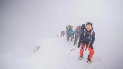 Bir dağcı oldukça dik bir yerde tüm vücudu korumalı bir şekilde tırmanıyor.

