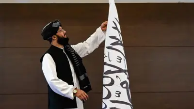 معاون سخنگوی وزارت خارجه حکومت طالبان در حال تنظیم پرچم طالبان.