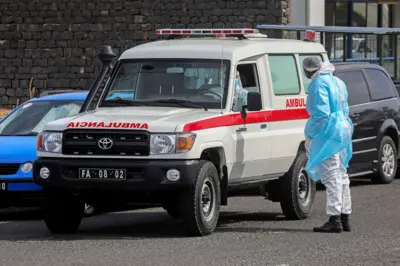 Akwụsịrị ụgbọ ihe mberede ụdị gwongworo n'okporo ụzọ ebe onye yi uwe hazmat guzoro n'akụkụ ya na-agwa onye ọkwọ ụgbọ ala okwu, yikwa uwe hazmat, ka ha na-ebupụ mmadụ n'ụgbọ ahụ gaa ọdụ ụgbọ elu ka ebufe ya na Netherlands maka ọgwụgwọ, na Cape Verde na Wednesde.