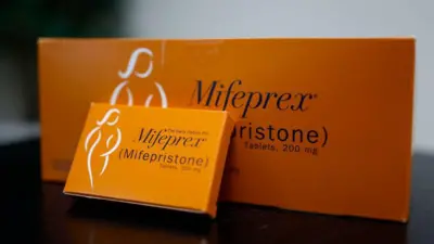 ミフェプリストンという黒い文字と、白色で女性のシルエットが印刷された、オレンジ色の箱のクローズアップ写真