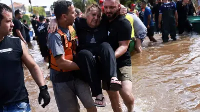 Homens carregando mulher durante enchente