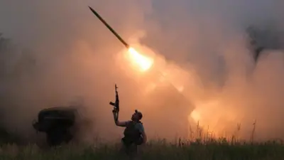 A Ukrainian soldier from the 93rd Kholodnyi Yar Separate Mechanized Brigade of the Ukrainian Armed Forces reacts as his colleagues fire a BM-21 Grad multiple launch rocket system towards Russian troops