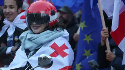 Грузия, женщина на мотоцикле, завернутая в флаг